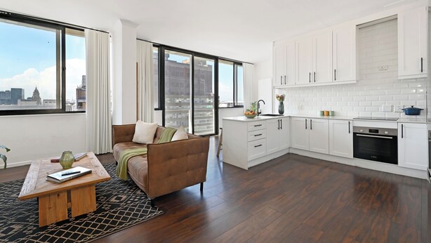 Ein modernes Apartment mit Wohnbereich, Küche und großen Fenstern mit Blick auf die Stadt.