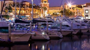 A marina with boats docked, a prominent tower, and buildings with balconies. - Nauti Baja- Condo at The Marina/Near the Beach! (Cabo San Lucas)