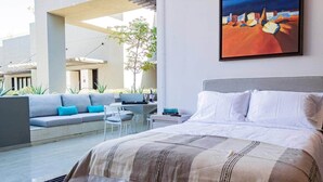 A bedroom with a bed, a sofa, a small table, and a painting on the wall. - Nauti Baja- Condo at The Marina/Near the Beach! (Cabo San Lucas)