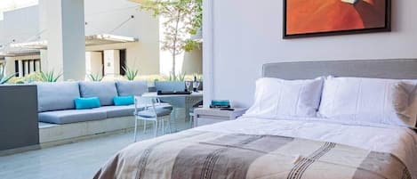 A bedroom with a bed, a sofa, a small table, and a painting on the wall.
