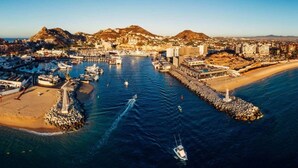 An aerial view of a coastal town with a marina, buildings, and a mountain in the background. - Nauti Baja- Condo at The Marina/Near the Beach! (Cabo San Lucas)