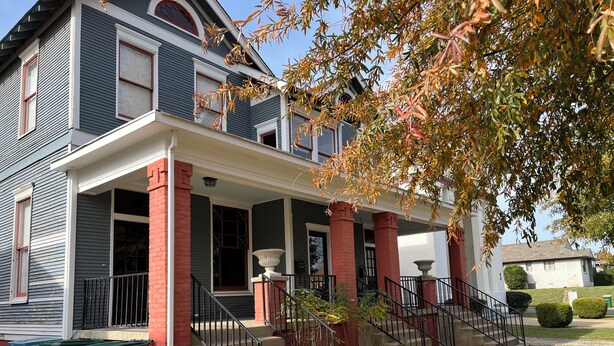 A two-story house with a front porch, a staircase, and a large window.