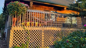 A wooden cabin with a porch, a hammock, and a lattice fence. - Private Oceanfront Log Home nestled right on the world famous Bay of Fundy (Middleton)