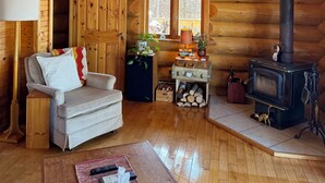 A log cabin interior with a sofa, a lamp, a fireplace, and a window. - Private Oceanfront Log Home nestled right on the world famous Bay of Fundy (Middleton)