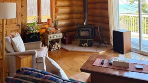 A cozy log cabin interior with a fireplace, wooden furniture, and a view of the outdoors. - Private Oceanfront Log Home nestled right on the world famous Bay of Fundy (Middleton)
