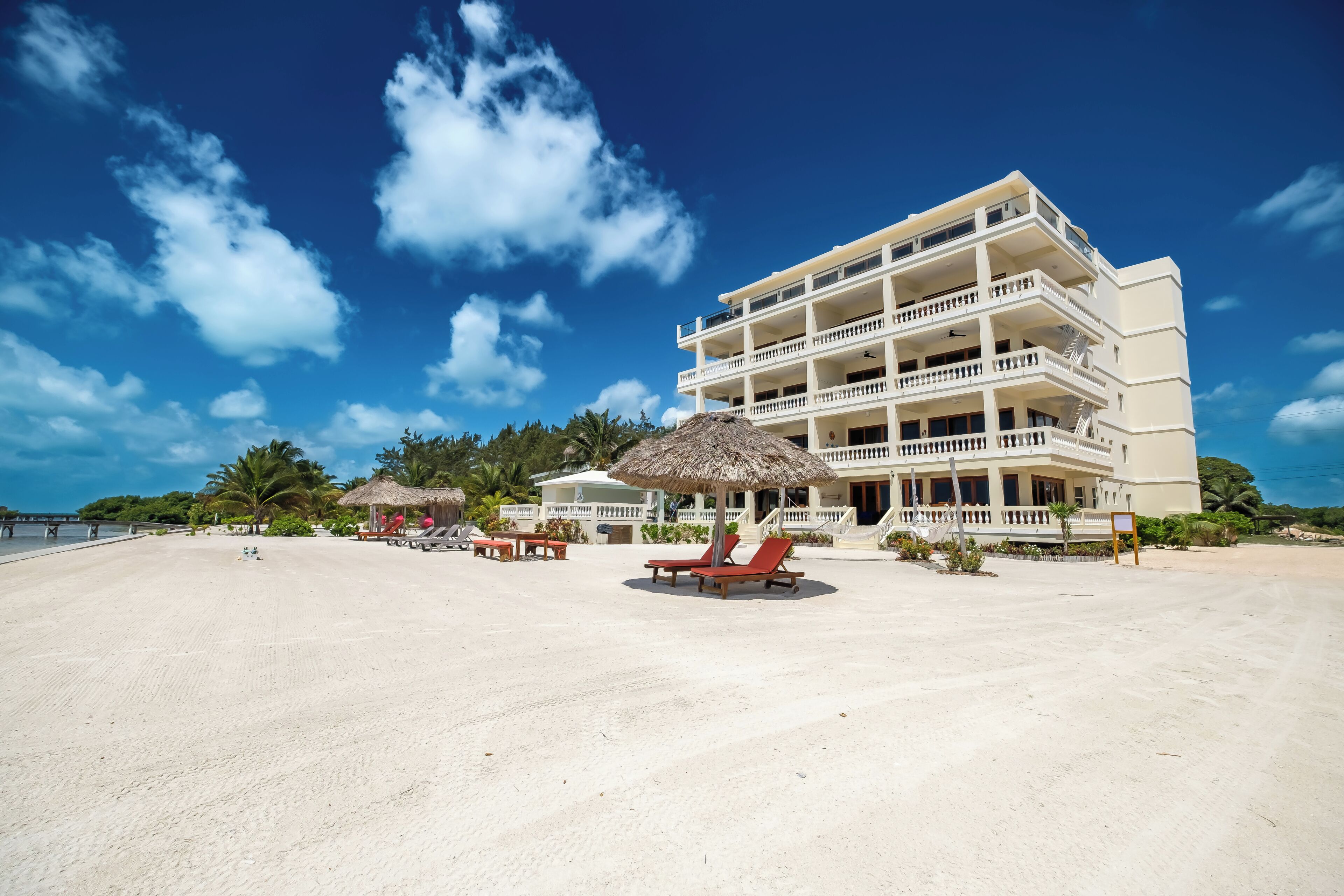 A beachfront hotel with multiple balconies, a sandy beach, and a clear blue sky.