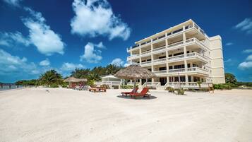 A beachfront hotel with multiple balconies, a sandy beach, and a clear blue sky.