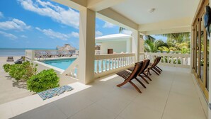 A balcony with a pool, lounge chairs, and a view of the ocean. - Oceans Edge Resort & Spa (San Pedro)