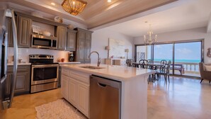 A modern kitchen with stainless steel appliances, a dishwasher, and a large island. - Oceans Edge Resort & Spa (San Pedro)
