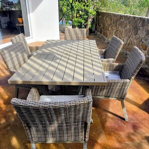 Un patio con tavolo e sedie, un muro in pietra e vista su una casa.