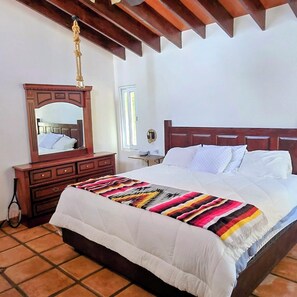 Ein Schlafzimmer mit einem Holzbett, einem Schminktisch, einem Spiegel und einem Fenster.