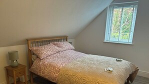 Ein Schlafzimmer mit einem hölzernen Bett, einem Nachttisch mit Lampe und einem Fenster mit Jalousien.