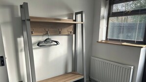 Ein Etagenbett mit Holzregal und Haken, ein Heizkörper und ein Fenster mit Jalousien.