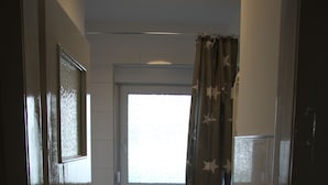 A bathroom with a toilet, a window, and a shower curtain with a star pattern. - Work Inn Rhein Ruhr Apartment (Duisburg)