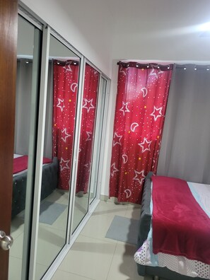 A bedroom with a bed, a sliding door, and a window with curtains. - Aromas of the sea (Santo Domingo)