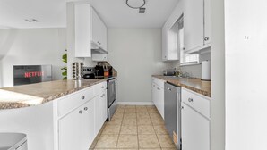 A modern kitchen with white cabinets, granite countertops, a built-in oven, and a dishwasher. - 1Br 1Bath Long Stays Near Fort Moore (Columbus)