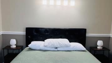 A hotel room with a bed, a headboard, a wall-mounted light fixture, and bedside tables with lamps.