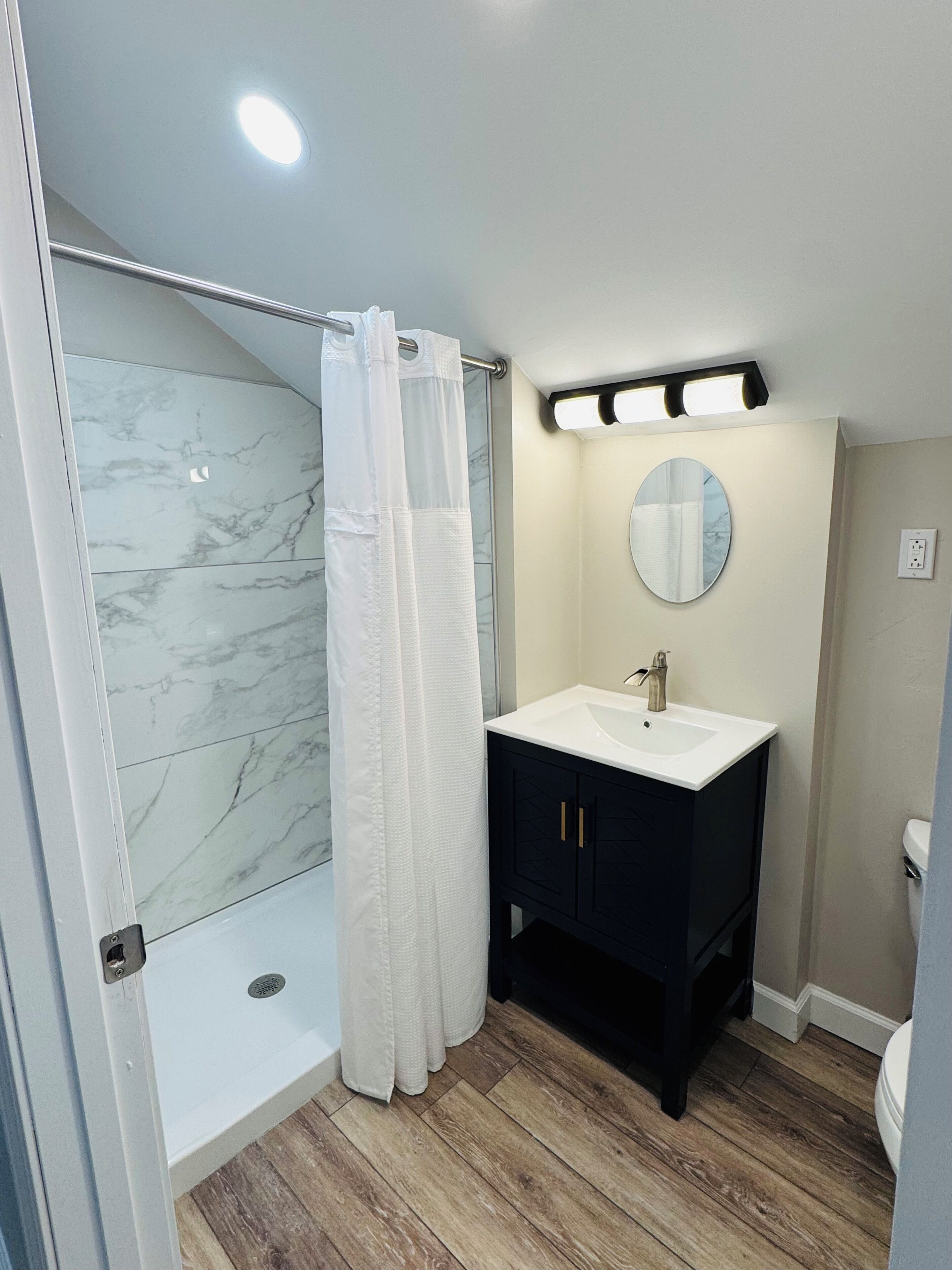 A bathroom with a shower, a sink, and a mirror.