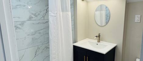 A bathroom with a shower, a sink, and a mirror.