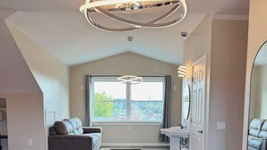 A dining area with a wooden table and black chairs, a large window with a view, and a modern chandelier. - Nestle Inn (Hermann)