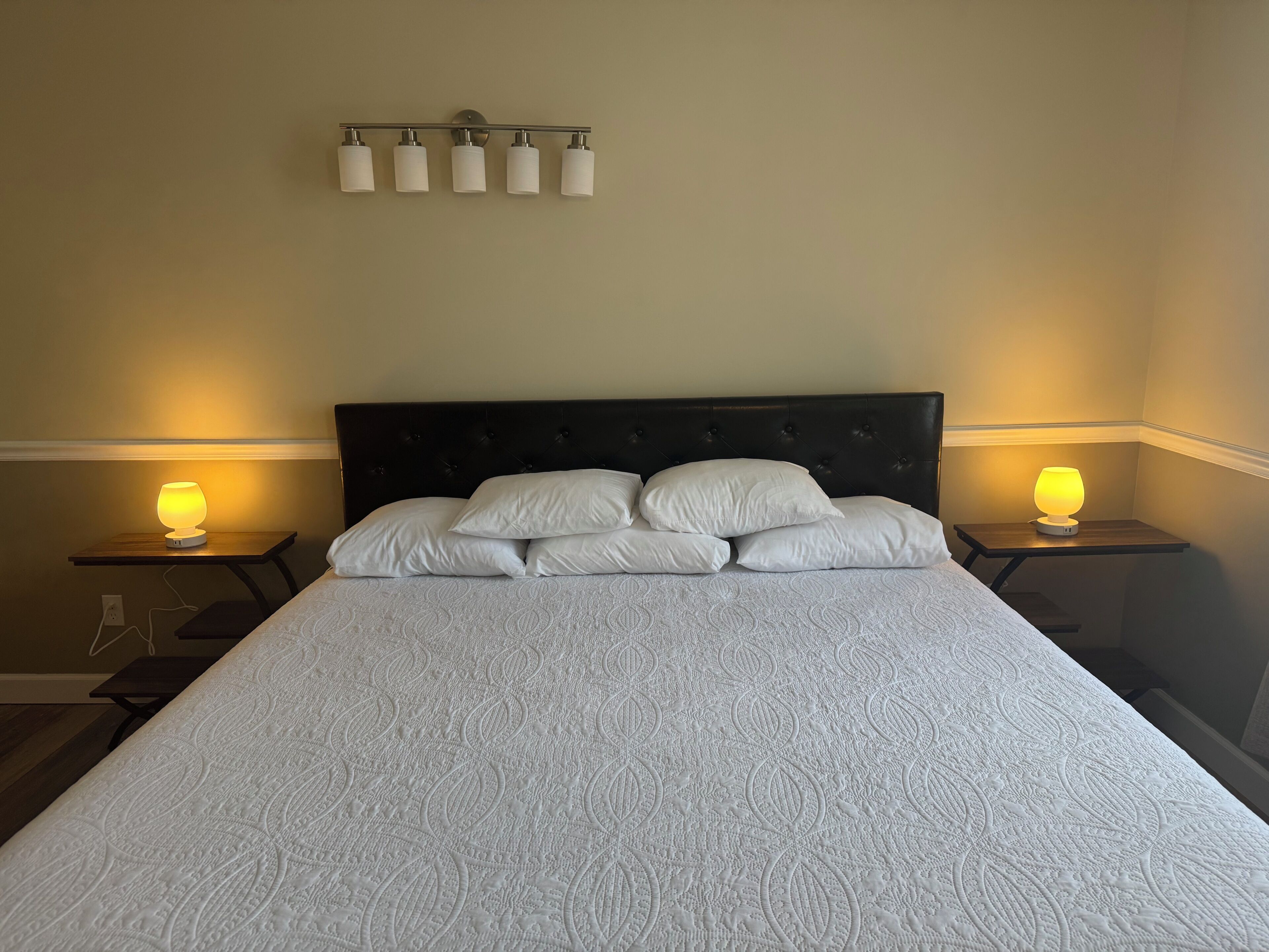 A bed with a patterned bedspread, a dark headboard, and two bedside lamps.