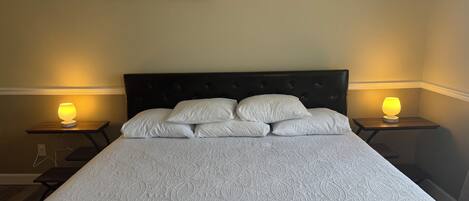 A bed with a patterned bedspread, a dark headboard, and two bedside lamps.