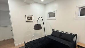 Ein Schlafzimmer mit Bett, Deckenventilator, Stehlampe und Fenster.