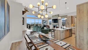 Uma cozinha moderna com armários de madeira, uma sala de jantar com uma mesa comprida e uma grande janela com vista para uma paisagem deslumbrante.