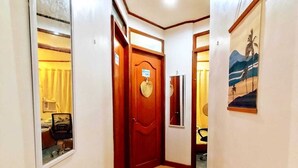 A hallway with a wooden door, a mirror, and a framed picture on the wall. - Amwani Residence - Westville (Puerto Princesa)