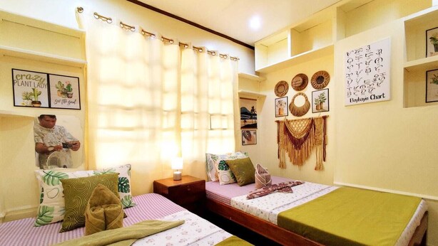 A room with two beds, a fan, a mirror, and a wall with decorative items. - Amwani Residence - Westville (Puerto Princesa)