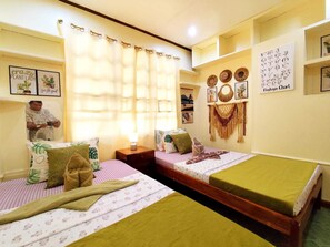 A room with two beds, a fan, a mirror, and a wall with decorative items. - Amwani Residence - Westville (Puerto Princesa)