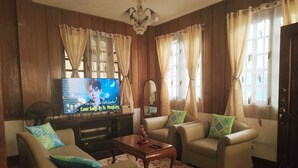 A living room with a television, two sofas, a coffee table, and a decorative mirror. - Amwani Residence - Westville (Puerto Princesa)