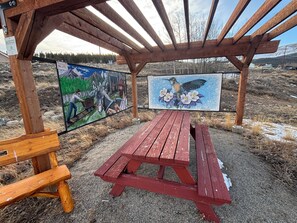 Un pabellón de madera con una mesa de picnic y bancos, con dos murales en las paredes.