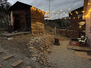 Una cabaña rústica con fachada de madera, un sendero de piedra y una zona de fogata.