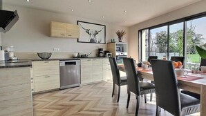 Una cocina moderna con comedor, muebles de madera y un amplio ventanal con vistas.
