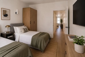 Une chambre d’hôtel avec deux lits, une armoire, une table de chevet avec une lampe, un téléviseur à écran plat et une plante en pot.