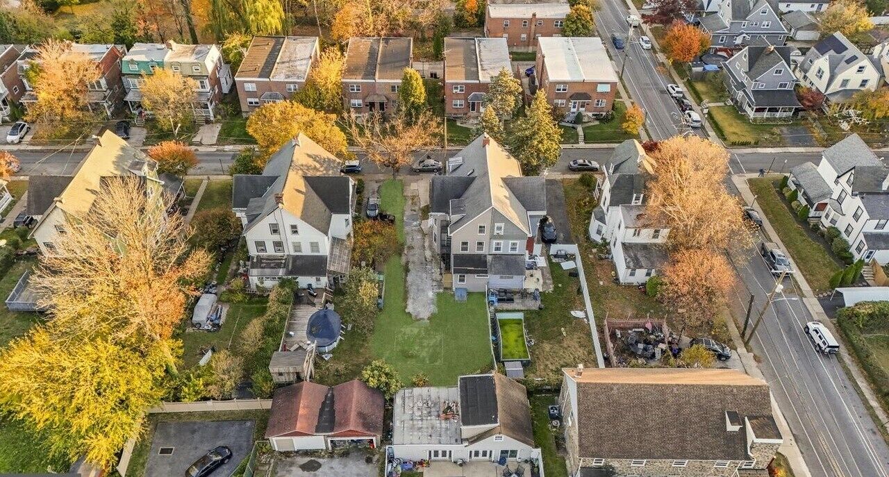 Vue aérienne d’un quartier résidentiel avec des maisons, des rues et des voitures garées.