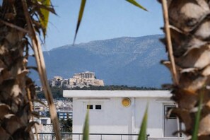 A building with a white facade and a circular window, overlooking a historic site with ancient ruins. - My Bouganvilla Home Acropolis View Stay in Tavros (Moschato-Tavros)