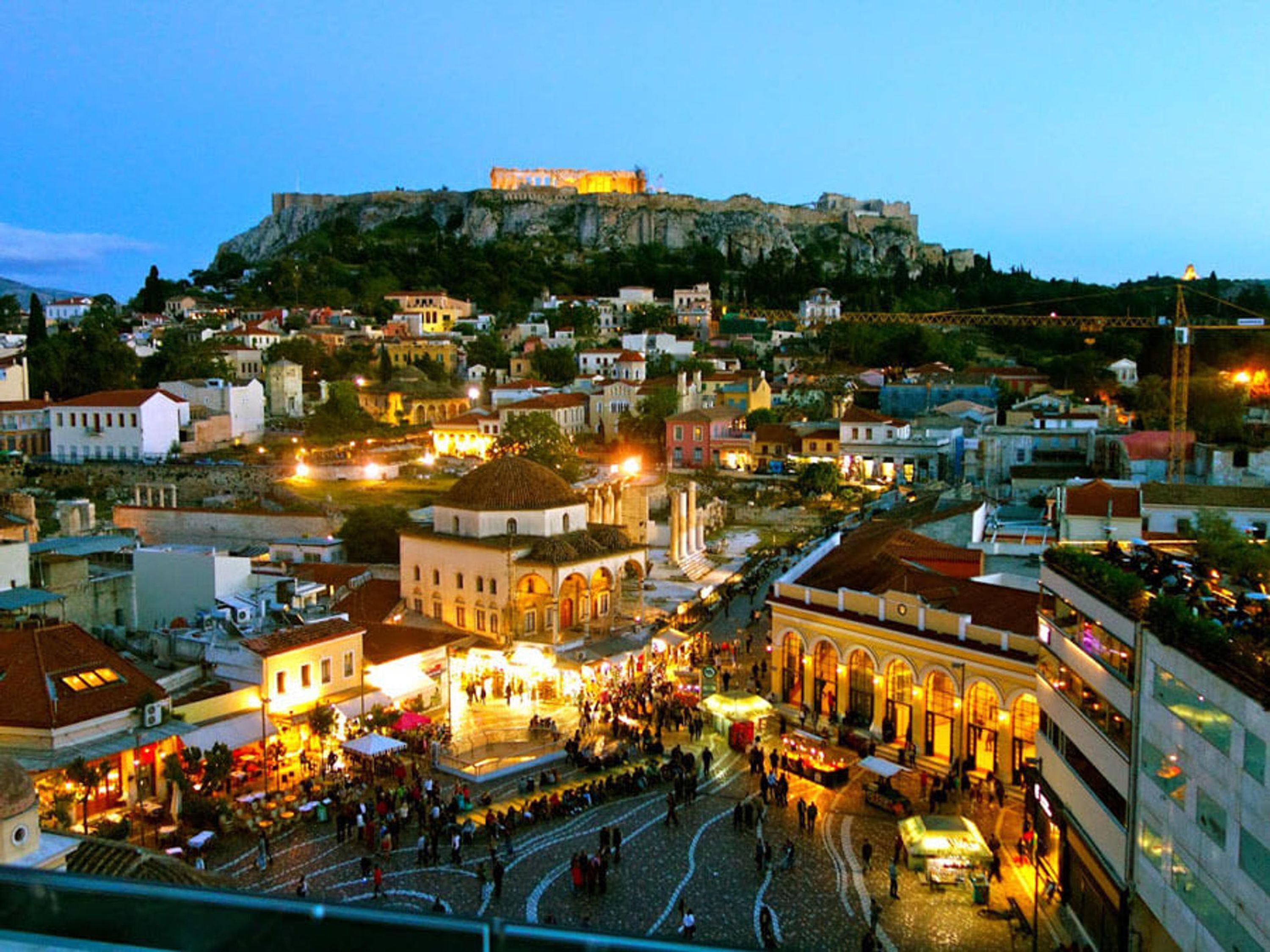 A historic cityscape with a prominent hilltop fortress, a bustling square with shops, and traditional architecture.
