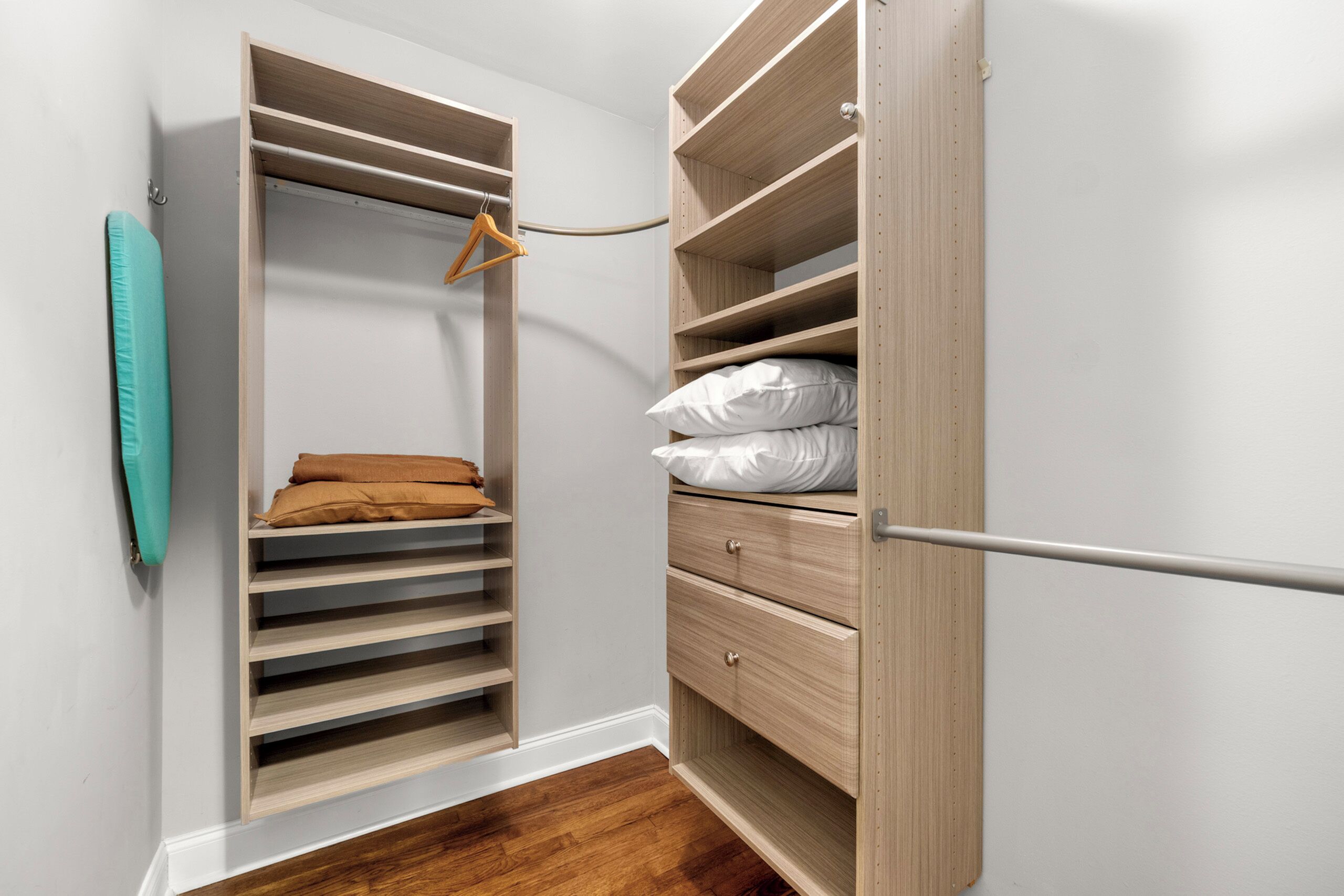 A walk-in closet with open shelves, a hanging rack, and a set of drawers.