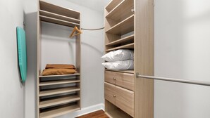 Ein begehbarer Kleiderschrank mit offenen Regalen, einer Kleiderstange und Schubladen.