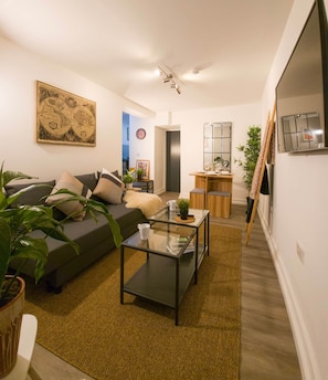 Ein modernes Wohnzimmer mit einer Couch, einem Couchtisch und einem Essbereich mit Holztisch und Stühlen.