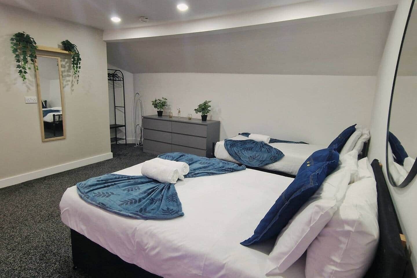 Habitación de hotel con cama, cómoda, espejo y una planta pequeña.