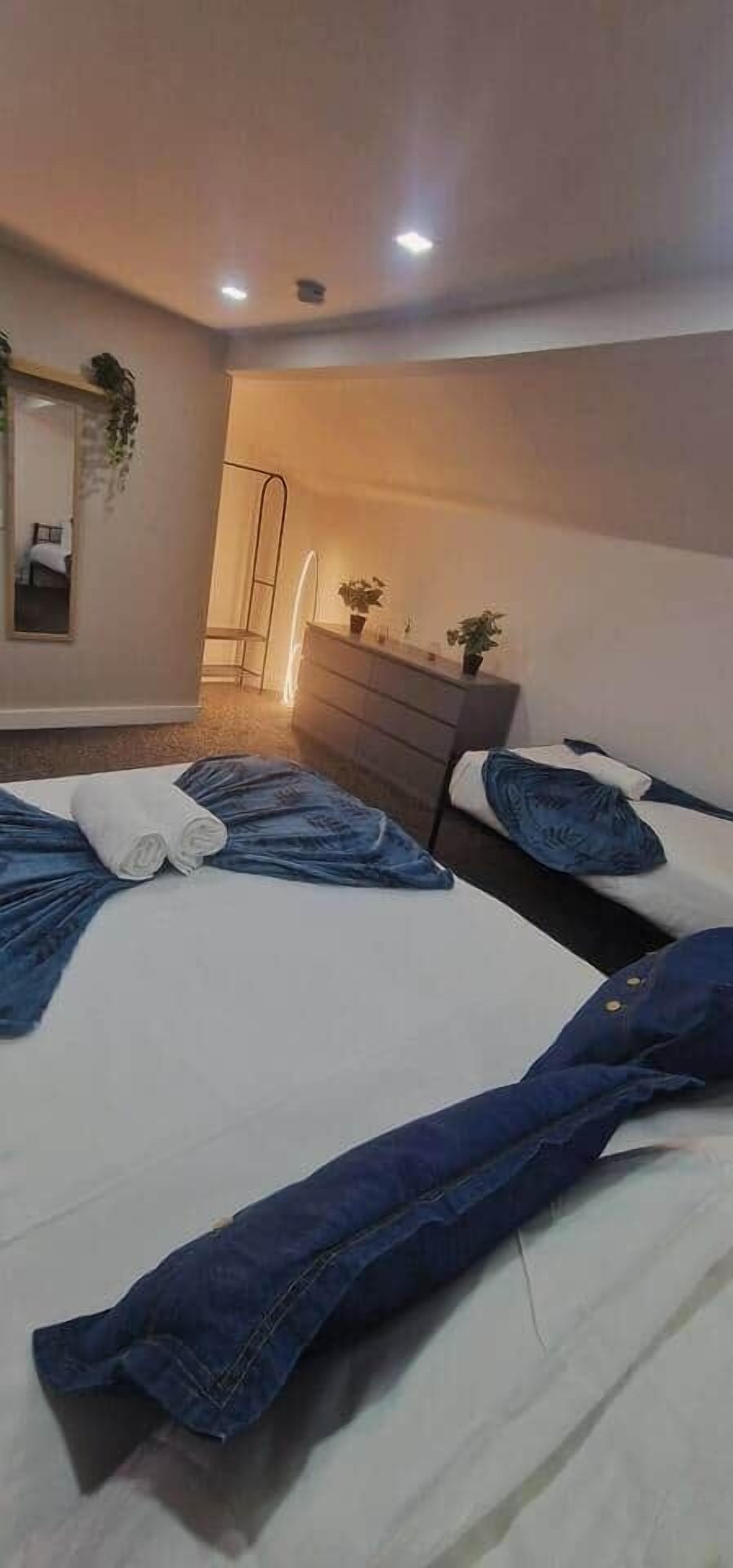 A hotel room with two beds, a dresser, a mirror, and a small plant.