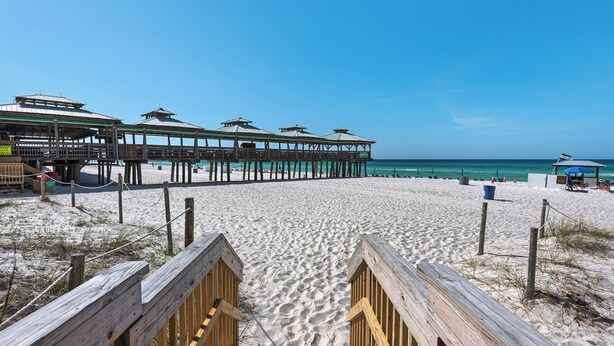 Ein Strand mit Holzstegen, die zu einem Steg mit mehreren Kiosken führen.
