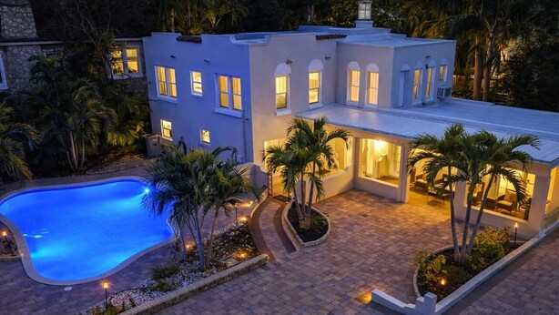 Une maison moderne dotée d’une piscine, de nombreuses fenêtres et d’un patio bien éclairé.