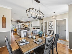 A dining area with a wooden table, chairs, and a hanging light fixture. - The Bourbon Embassy at Twin Creeks (Winchester)