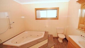 Ein Badezimmer mit Badewanne, Toilette und einem Fenster über der Toilette.