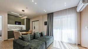 Ein modernes Wohnzimmer mit einer Eckcouch, einem Esstisch und einer Küchenzeile mit einer Mikrowelle.