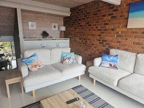 A living room with two sofas, a coffee table, and a brick wall. - Amazing view from this centrally located 2 bed unit in the heart of Merimbula. (Merimbula)